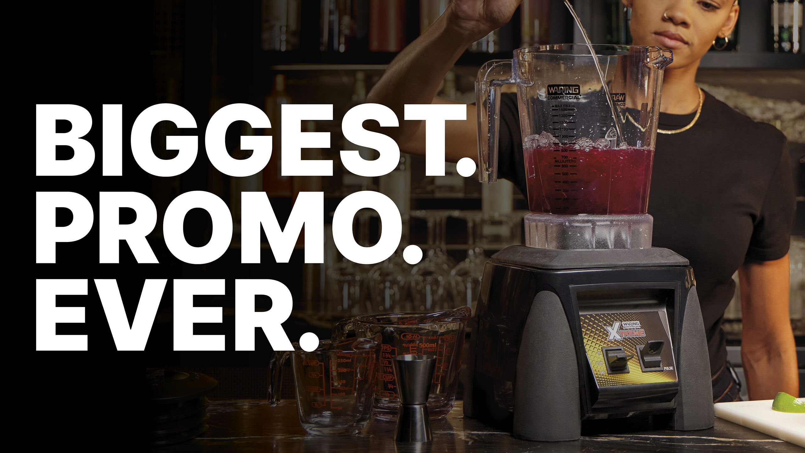 woman pouring ingredients into a blender while standing behind a bar